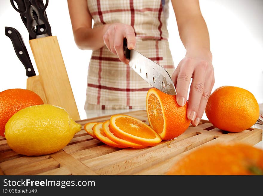 Girl cutting orange with the knife, on a wooden plate. Girl cutting orange with the knife, on a wooden plate