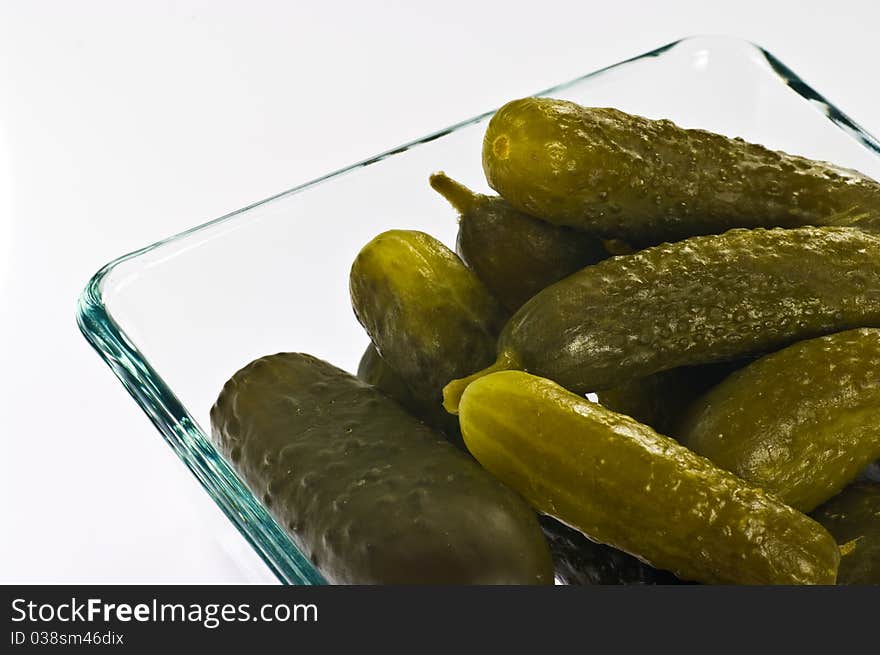 Pickled cucumbers in glass container on white background