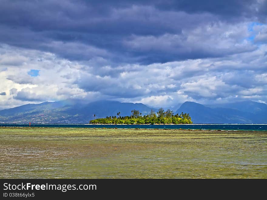 Motu is a small island on the reef, from Moorea island with Tahiti behind the clouds. Motu is a small island on the reef, from Moorea island with Tahiti behind the clouds.