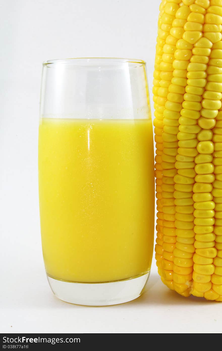 A glass of corn juice on a white background ,with corn by side