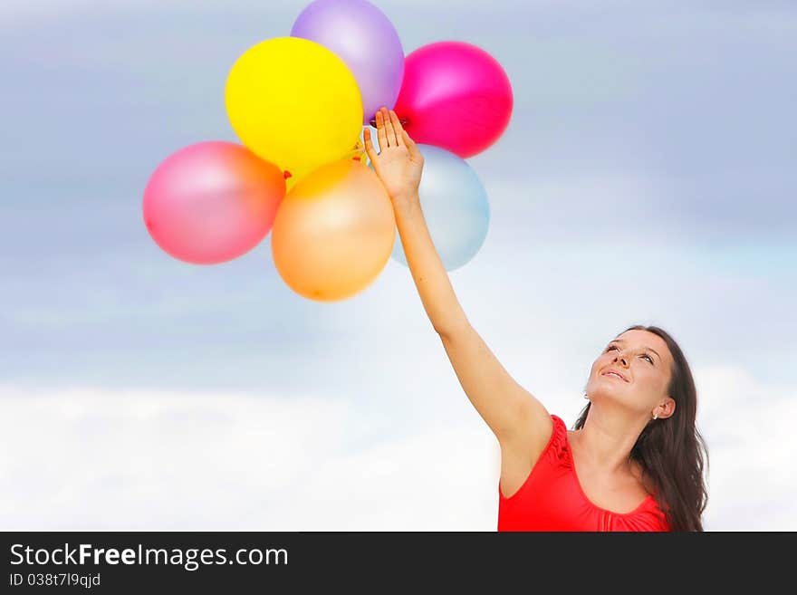 Young attractive woman with colorful balloons on sky background