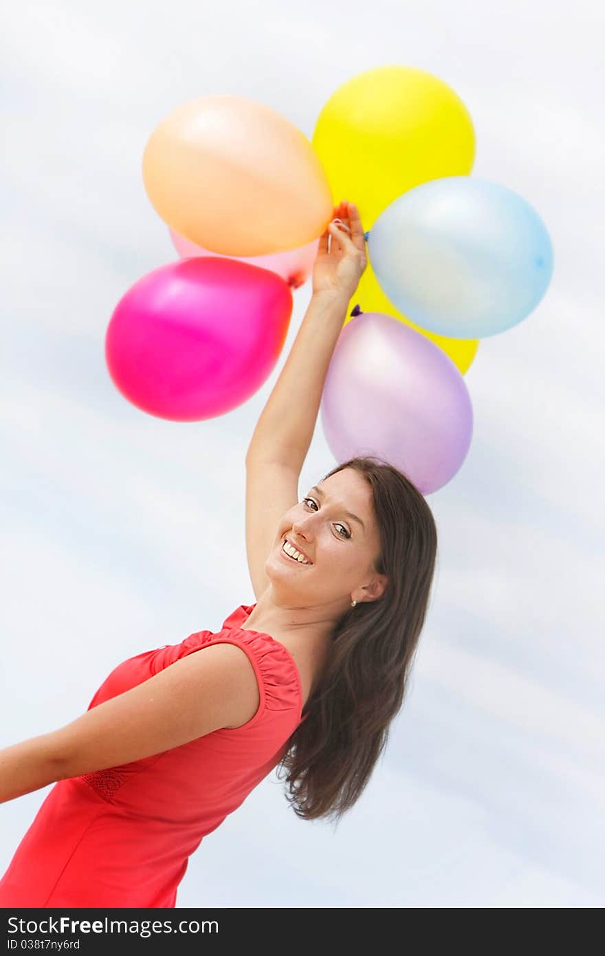 Young attractive woman with colorful balloons on sky background