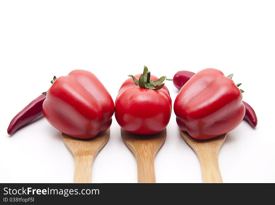 Red paprikas and tomato onto cook spoons