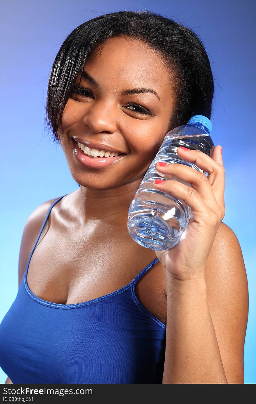 Portrait of beautiful black woman, with a big, happy smile. She is wearing a blue vest and holding a bottle of water. Portrait of beautiful black woman, with a big, happy smile. She is wearing a blue vest and holding a bottle of water.