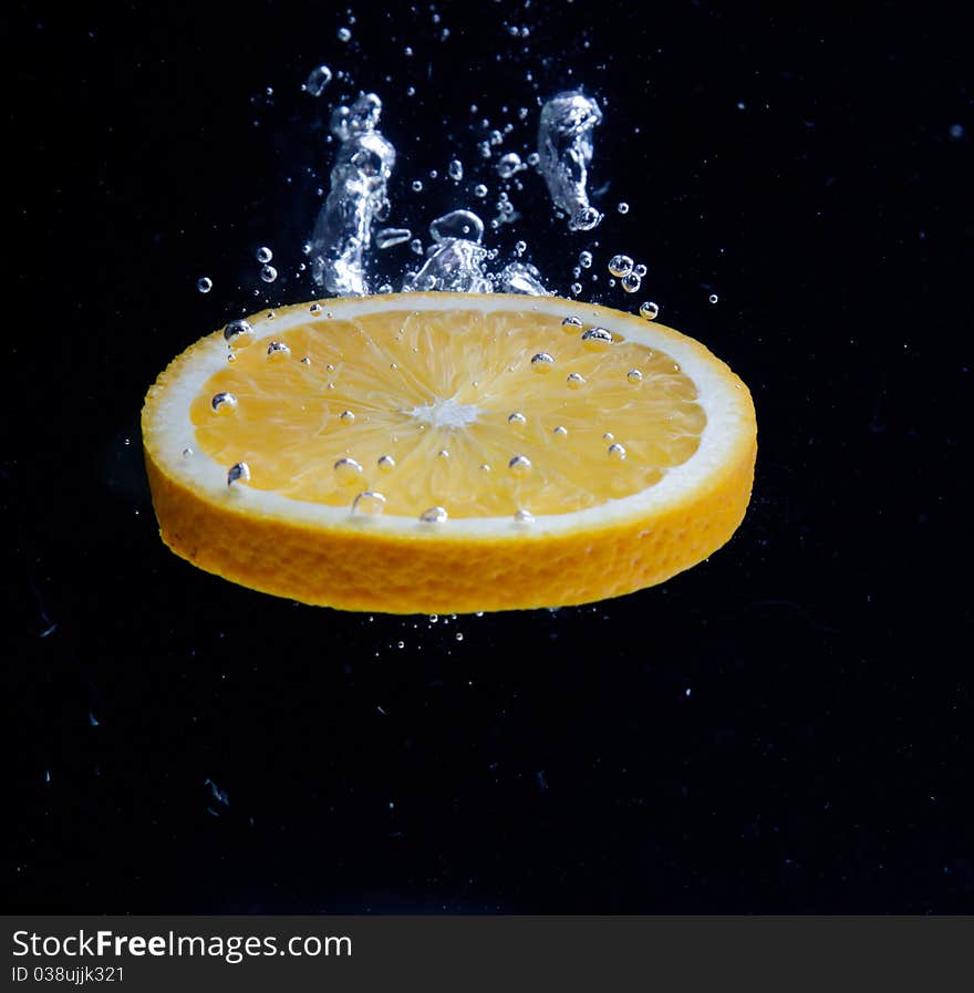 Orange and splash water over black background