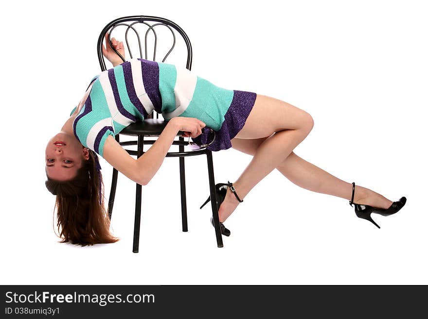 Girl in stripy blue dress bend down on stool. Isolated on white.