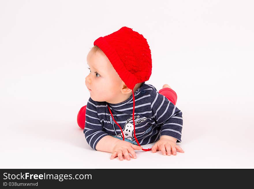 Little child baby in a red hat lying on the floor