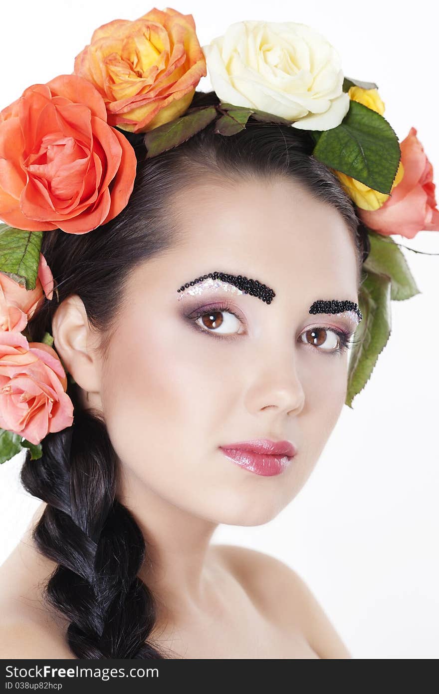 Portrait of young beautiful woman with roses in hair, on white background