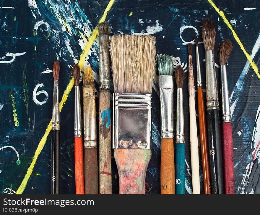 Paintbrushes lying on a blue-yellow paintig, art and craft equipment