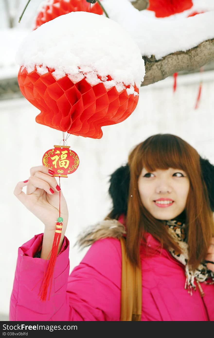 After New Year's first snow,it symbolizes good luck. Beautiful Chinese girl enjoying red lantern and Chinese knot in Chinese new year.(Focus on the lantern and knot) Chinese characters on Chinese knot are Good Fortune .