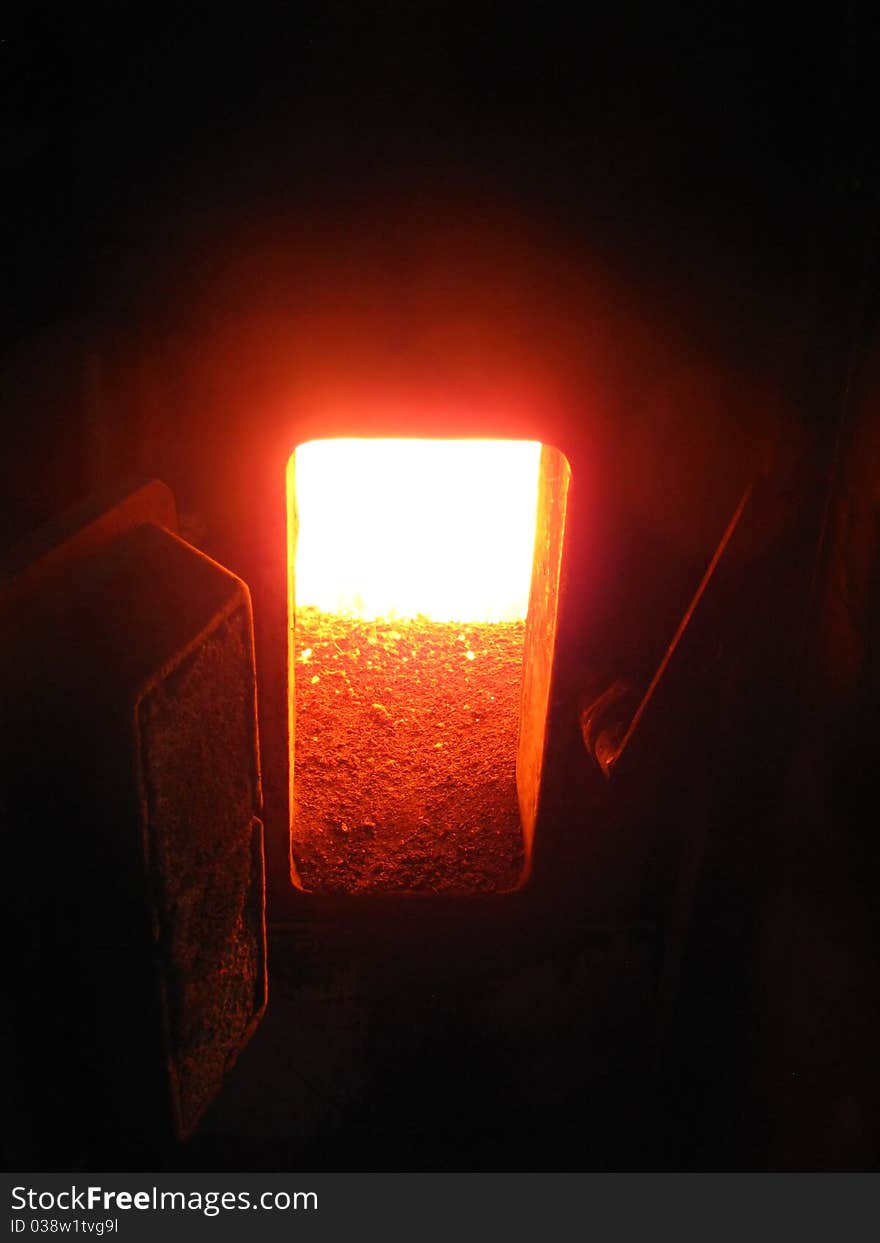 Fire in the coal boiler grate visible through an open manhole. Fire in the coal boiler grate visible through an open manhole