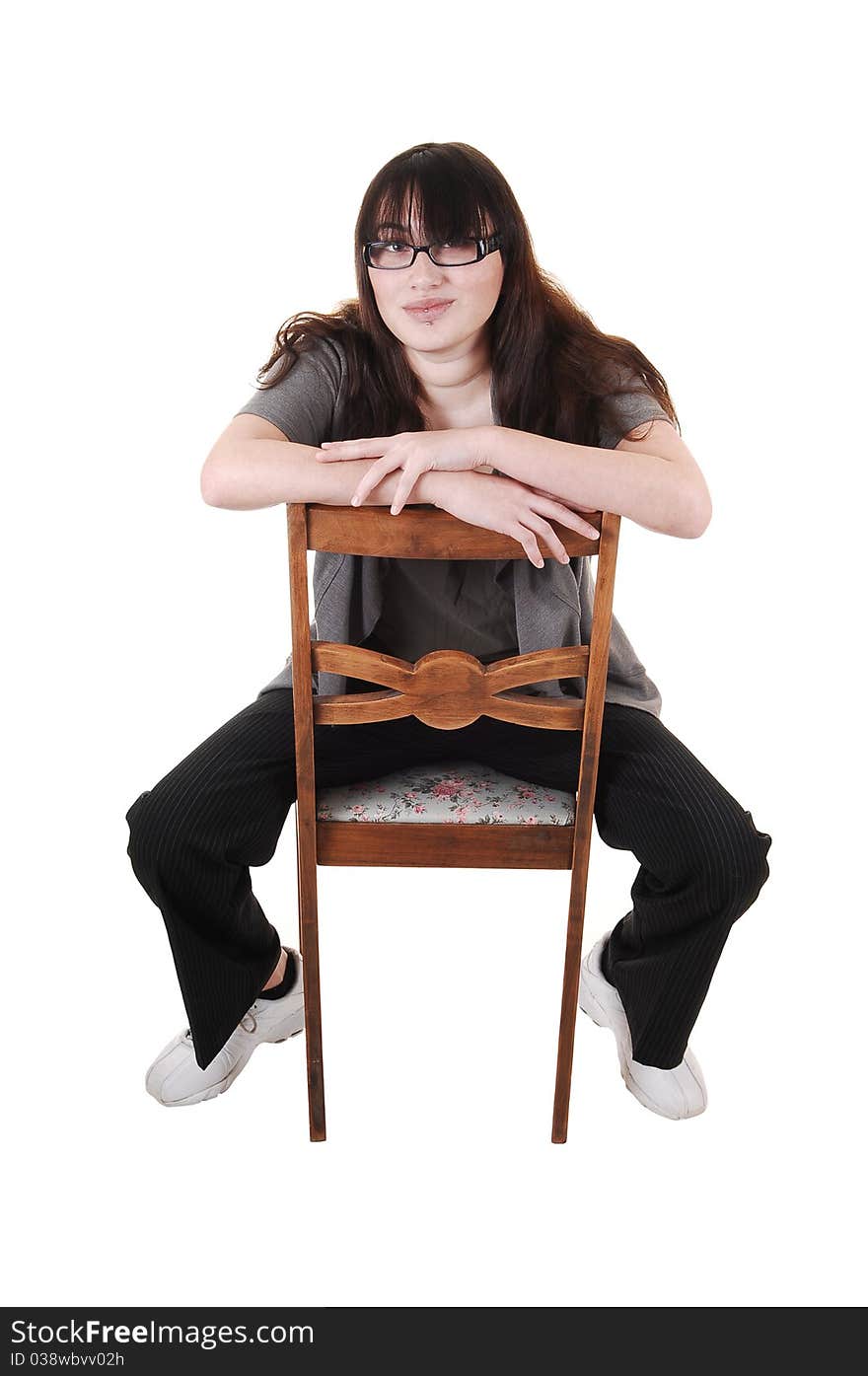 A young girl sitting backwards on an old chair, with glasses, for white background.