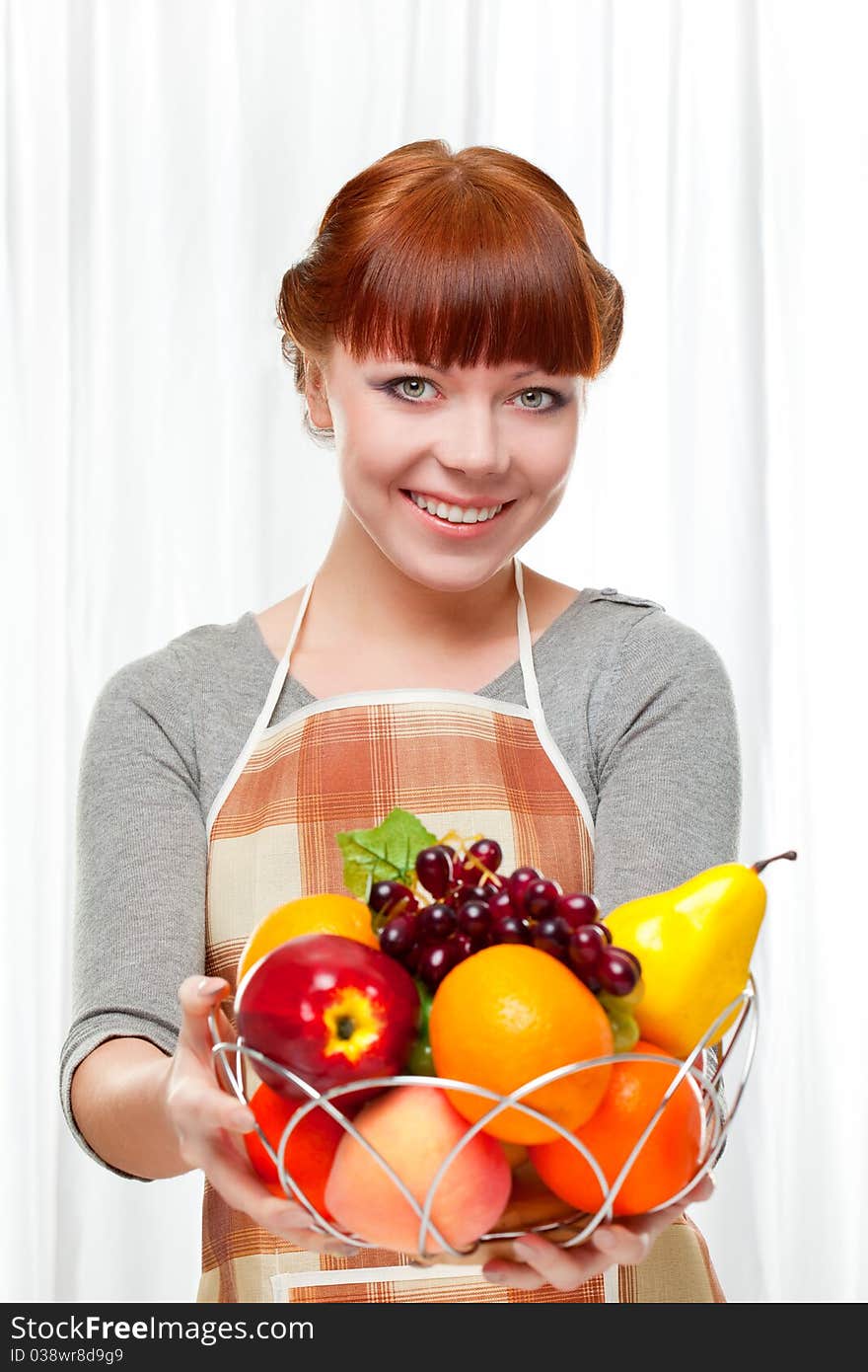 Ginger housewife holding fruits over white