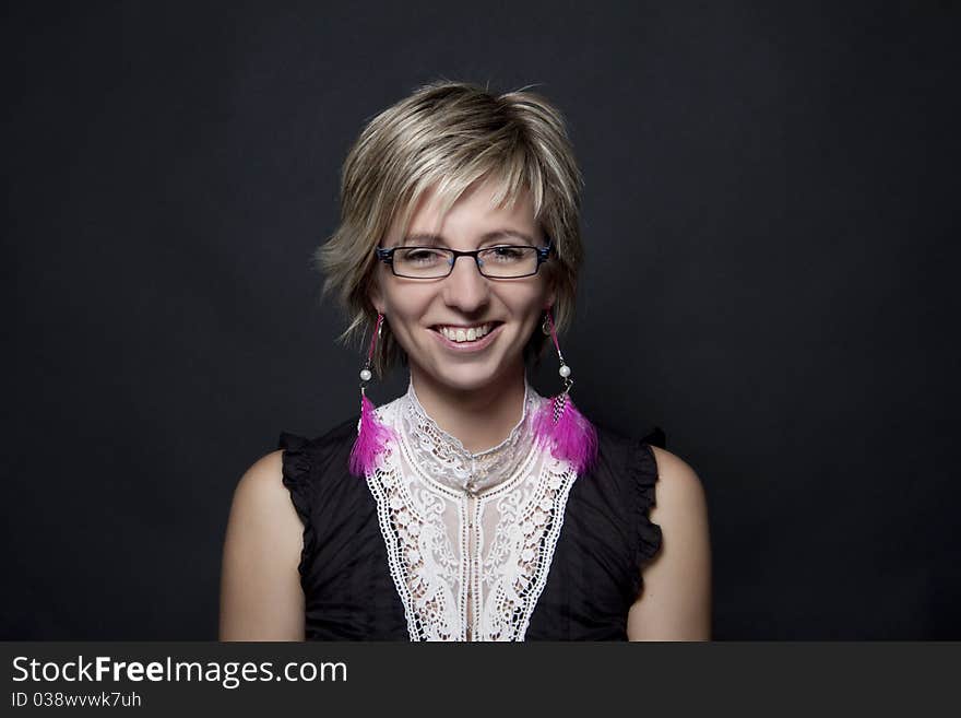 Portrait of attractive woman with pink feather earrings on black background. Portrait of attractive woman with pink feather earrings on black background