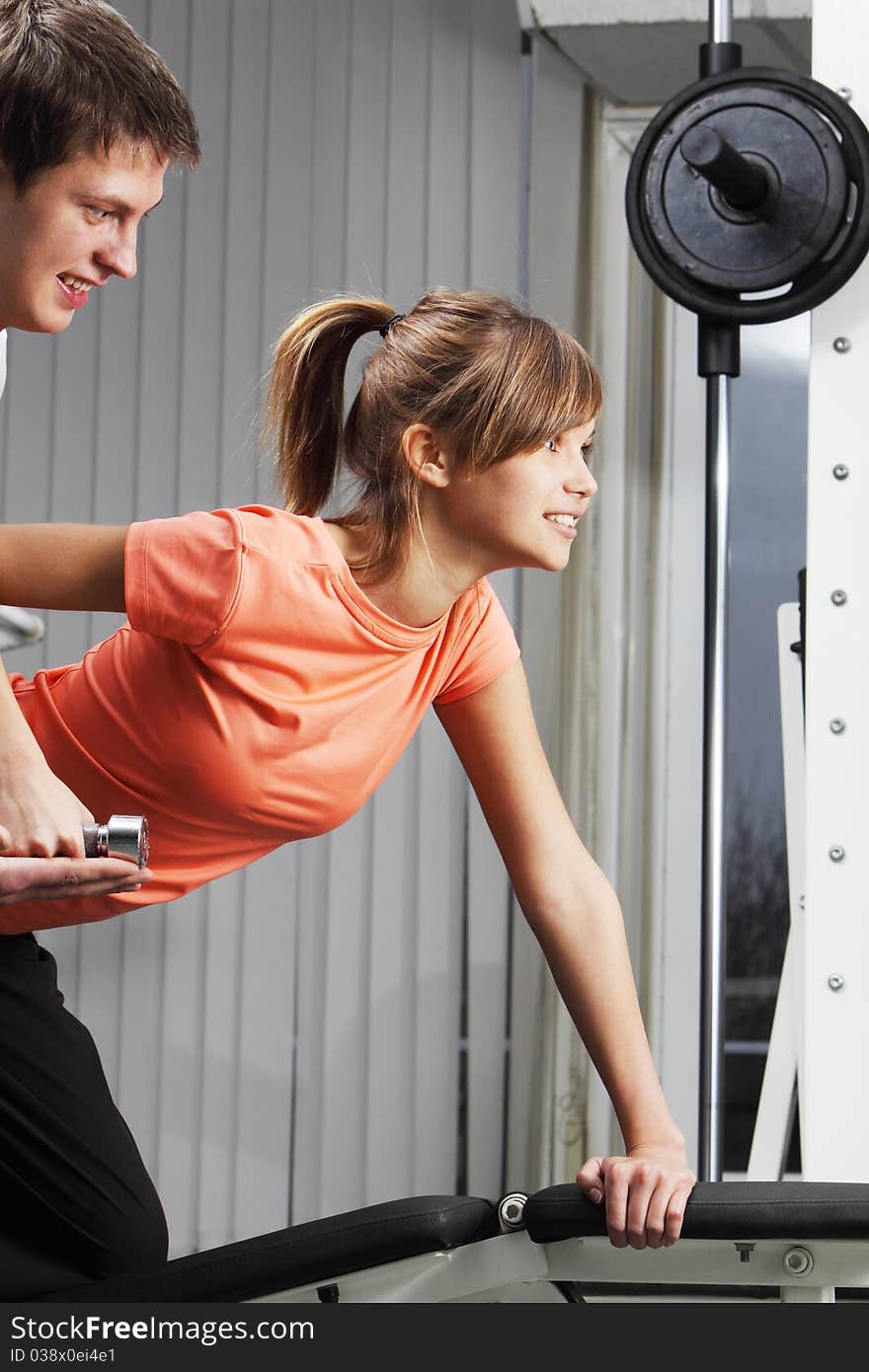 A girl's trainer shows her the correct form of exercise. A girl's trainer shows her the correct form of exercise