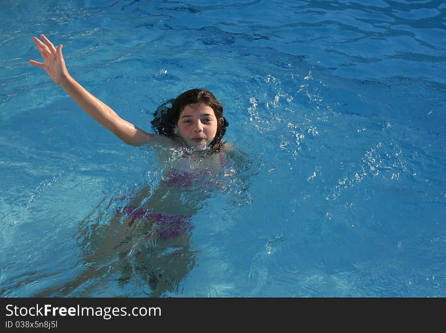 Girl swimming and waving to the camera.