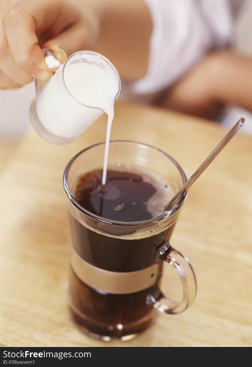 Hand Pouring Cream into Coffee