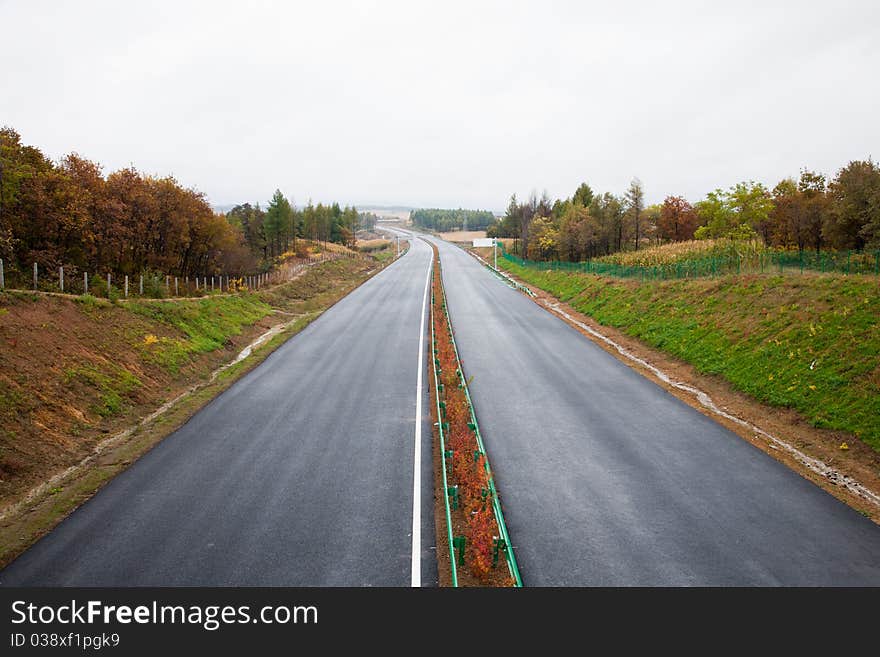 Highway through bushes and woods.