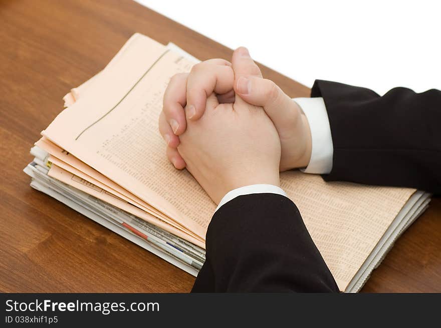 Hands of the businessman on a pile of newspapers close up