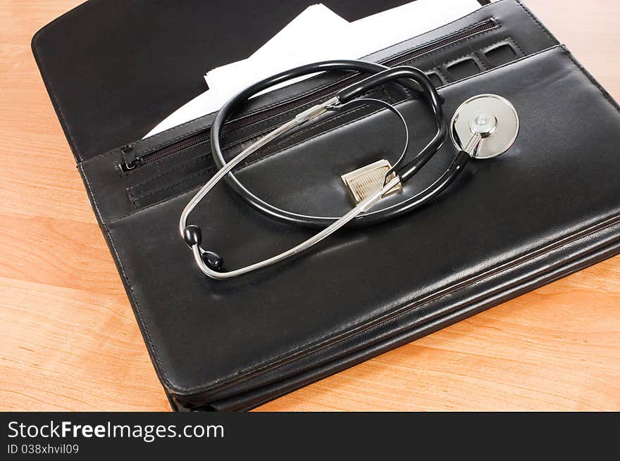 Black portfolio and phonendoscope on a table still life