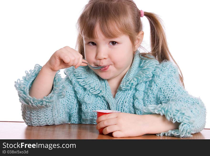 The little girl eats yoghurt on white