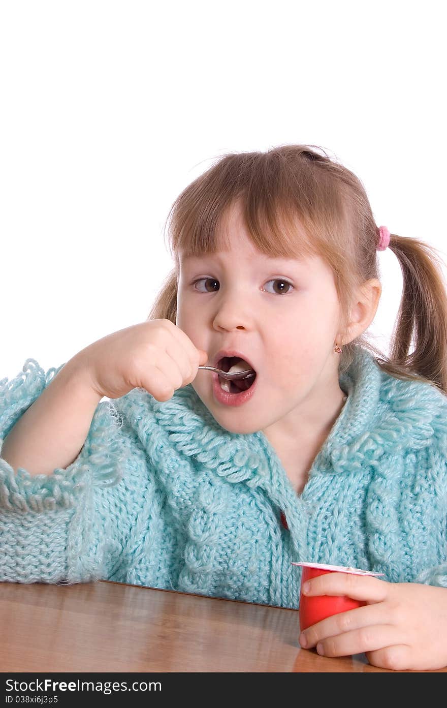 The little girl eats yoghurt on white