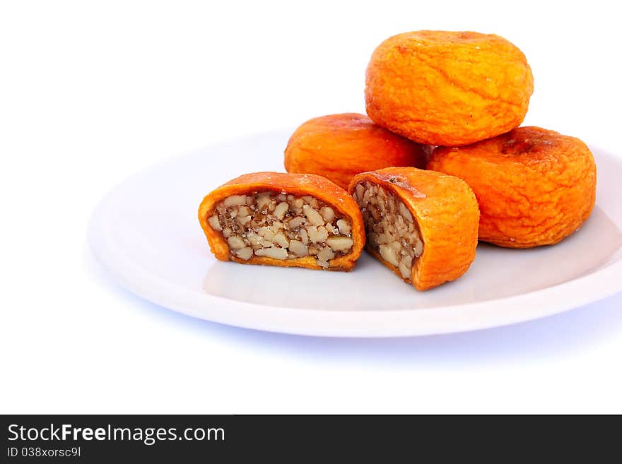 Dried peaches stuffed with nuts in plate isolated on white background.