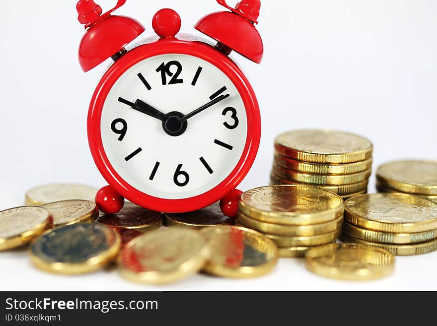 A red alarm clock on top of a pile of Golden coins, signifying time and investments go together. A red alarm clock on top of a pile of Golden coins, signifying time and investments go together.