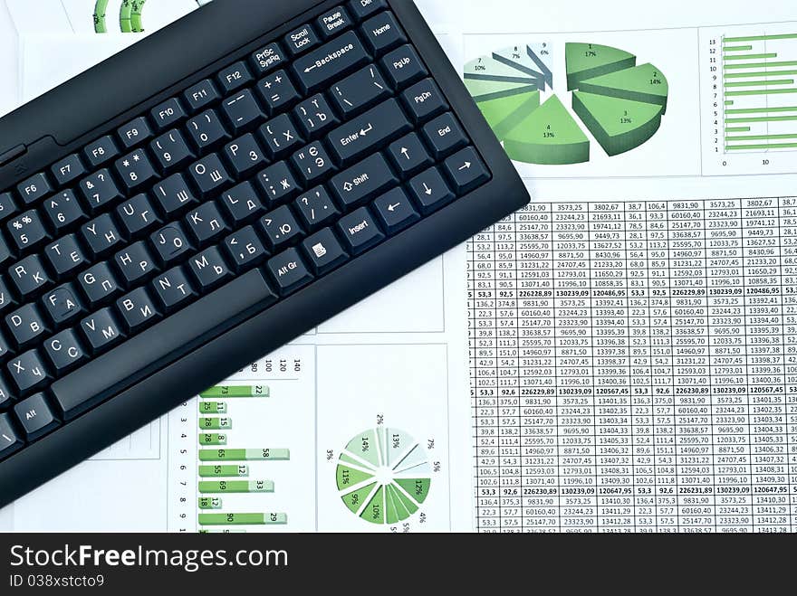 Black keyboard on a stock green chart and numbers. Studio shot. Black keyboard on a stock green chart and numbers. Studio shot