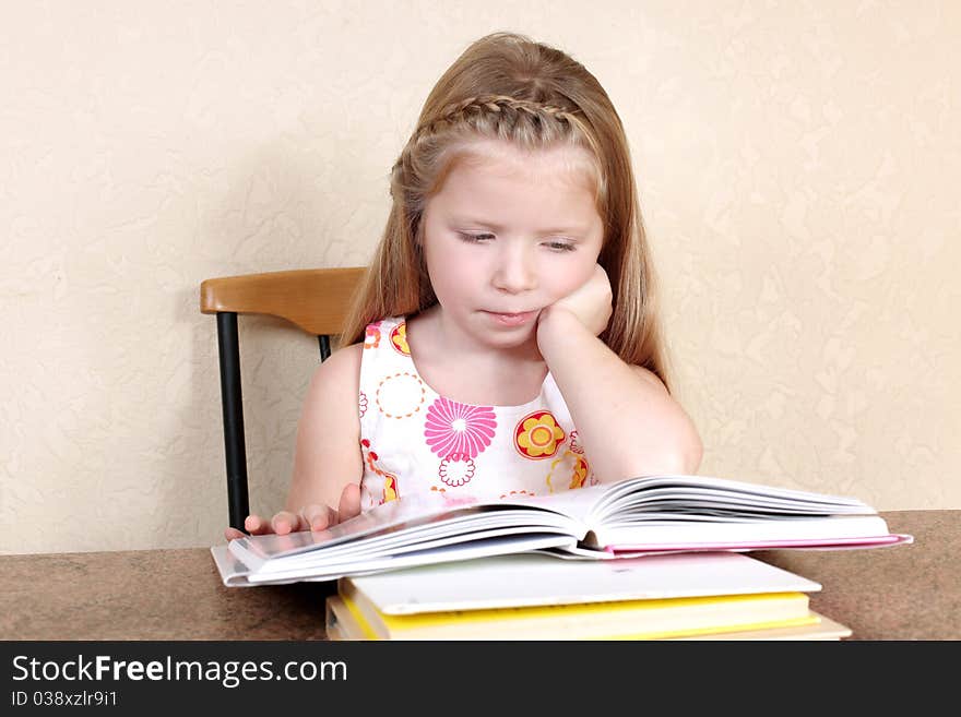 Little girl reading book against yellow wall at home