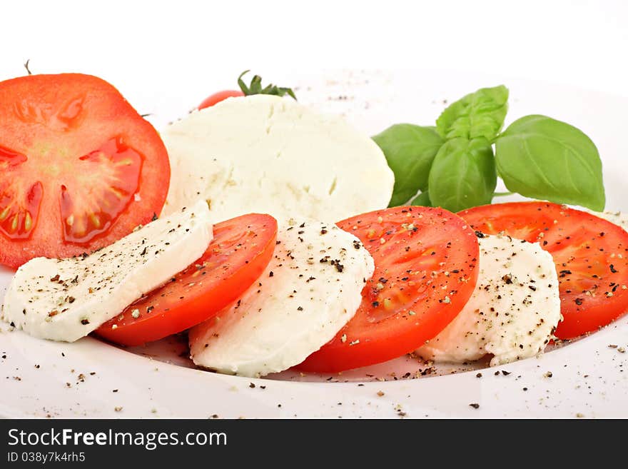 Mozzarella and tomato slices with pepper and basilicas. Mozzarella and tomato slices with pepper and basilicas.