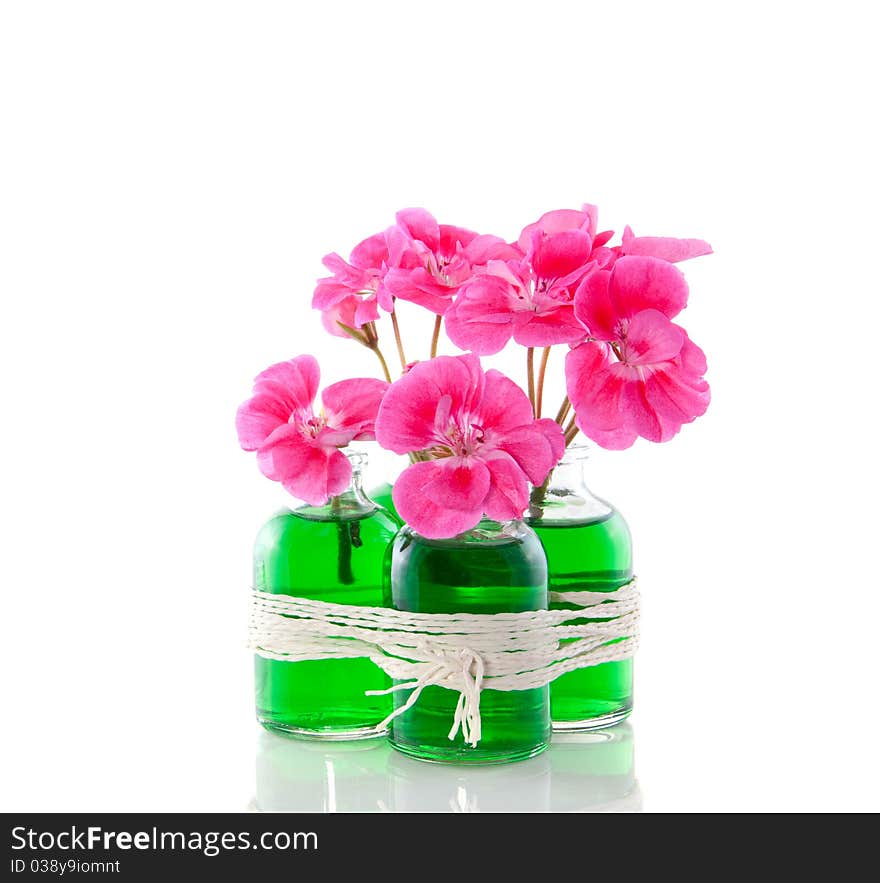 Pink geranium in four little glass vases with green liquid isolated over white. Pink geranium in four little glass vases with green liquid isolated over white