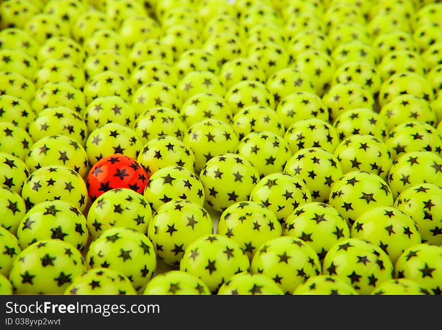 One red paintball among green paintballs