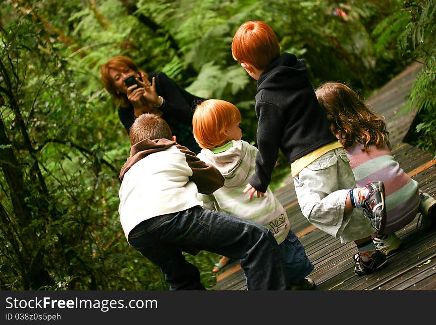 Red haired woman photographing a group of children in a forest. Red haired woman photographing a group of children in a forest