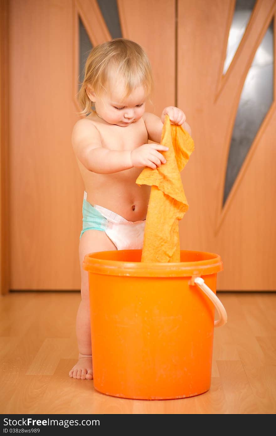 Adorable baby washing rug in orange pail