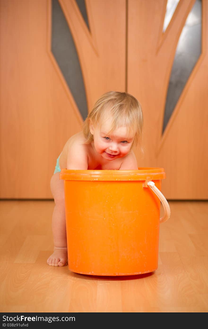 Adorable baby washing rug in orange pail