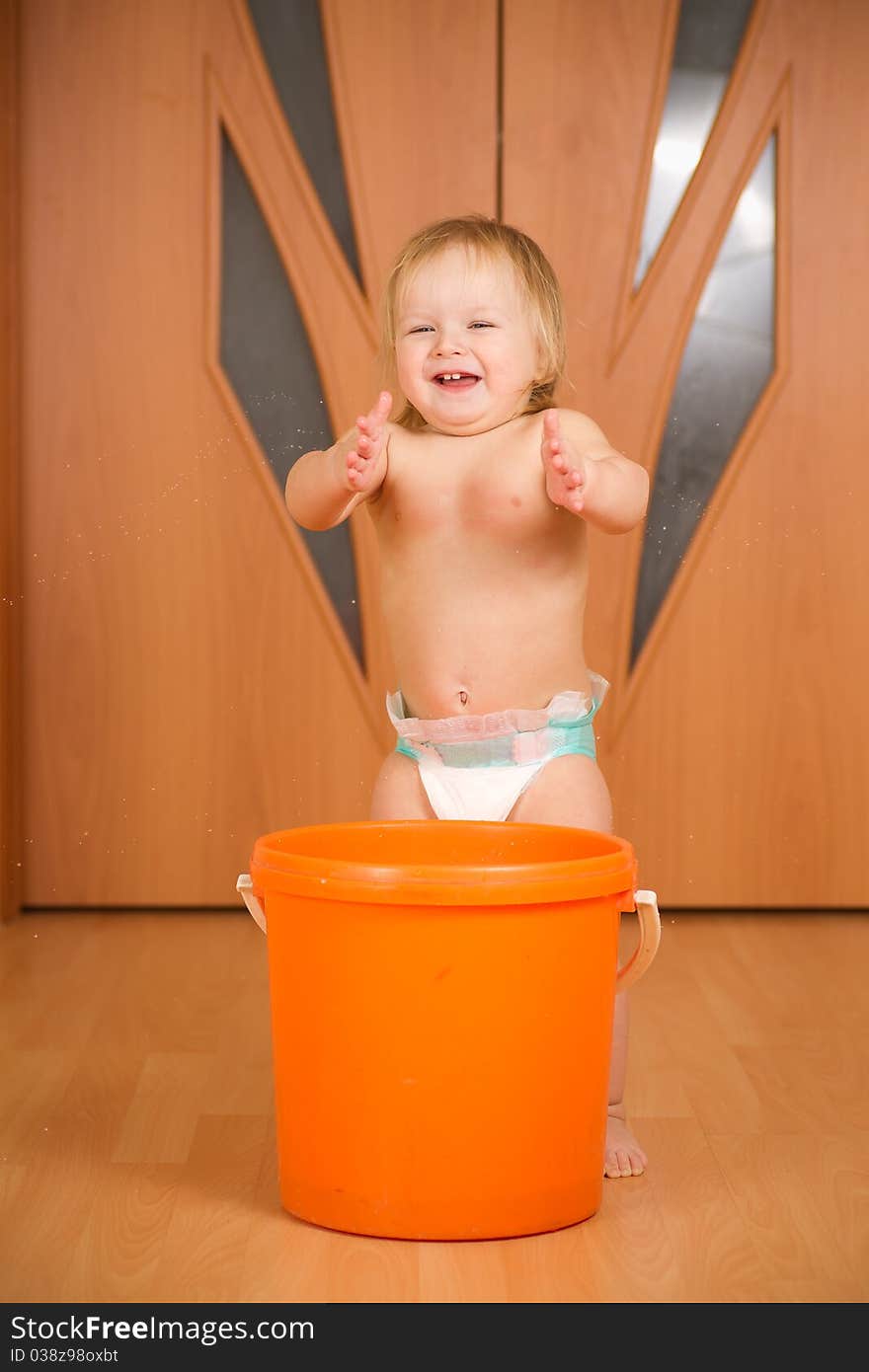 Adorable happy baby applause staying near orange pail washing floor