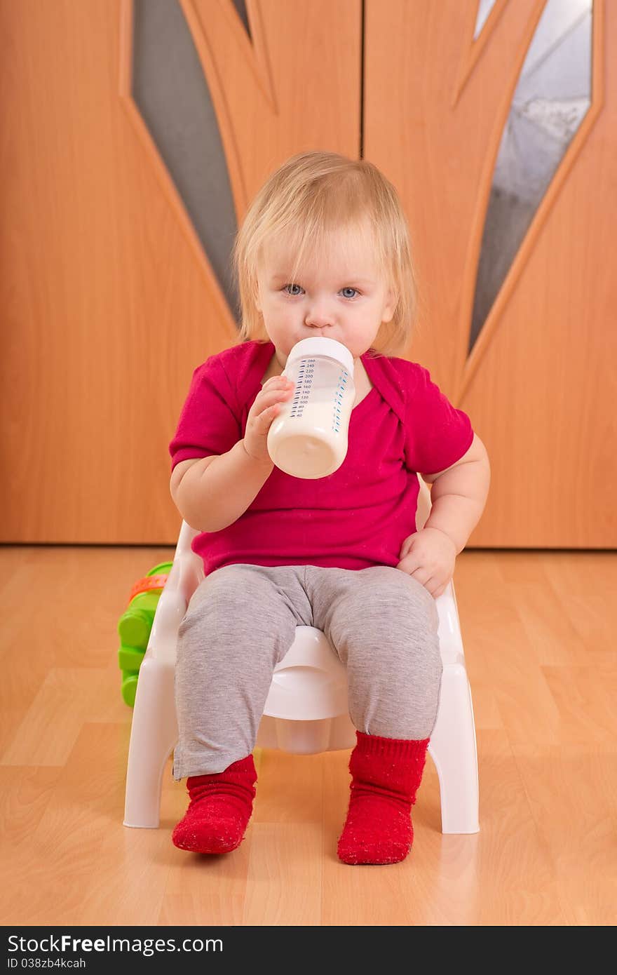 Adorable baby sit on baby chair toilet and drink milk from bottle. Adorable baby sit on baby chair toilet and drink milk from bottle