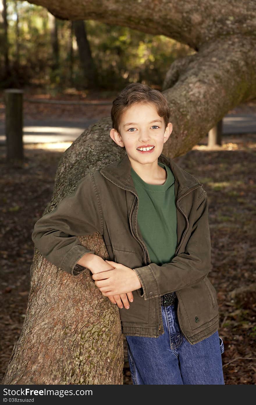 Outdoor portrait of young boy and large oak tree