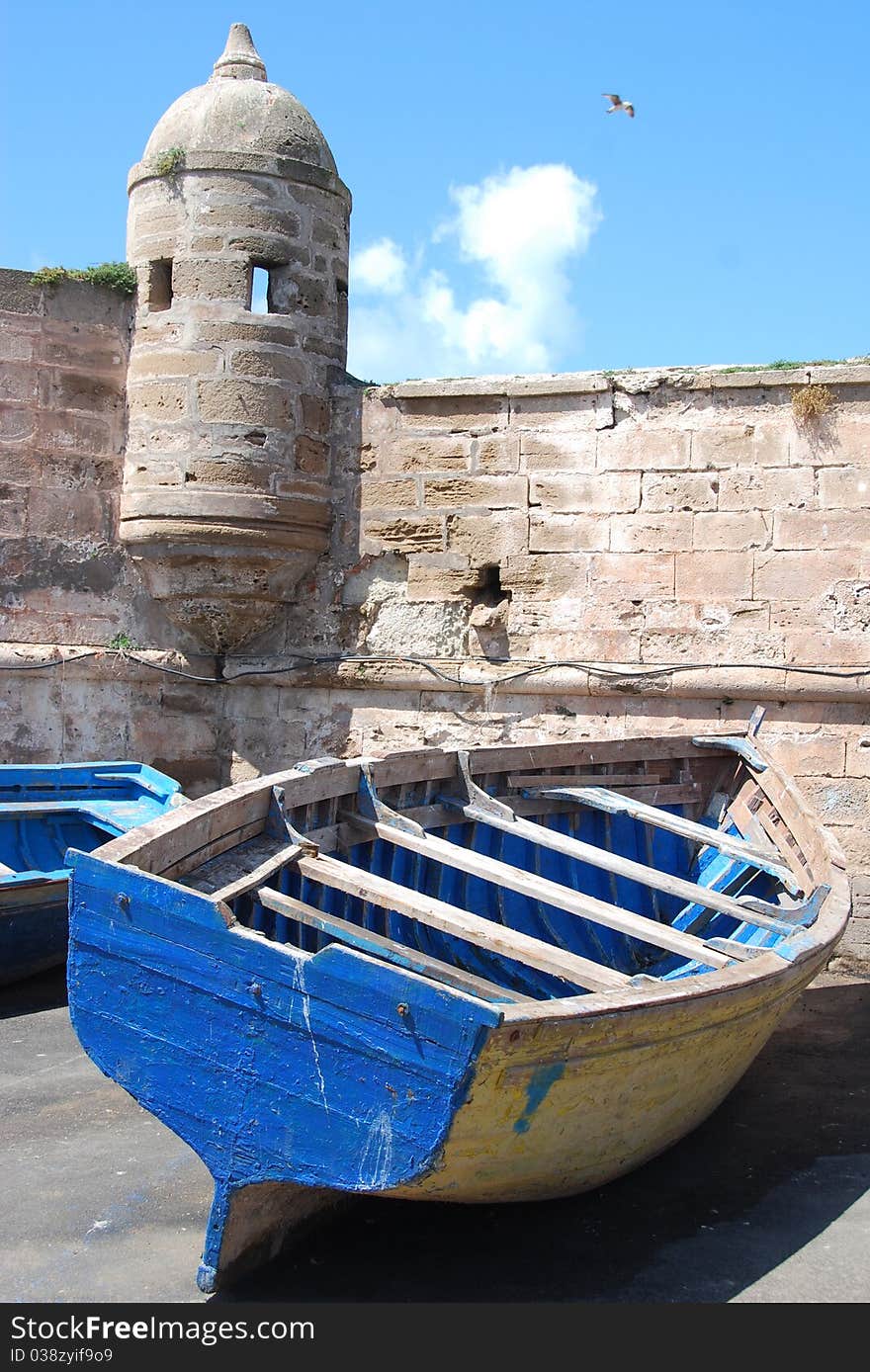 A colorful boat sits next to a medieval wall while waiting to go out to sea. A colorful boat sits next to a medieval wall while waiting to go out to sea.