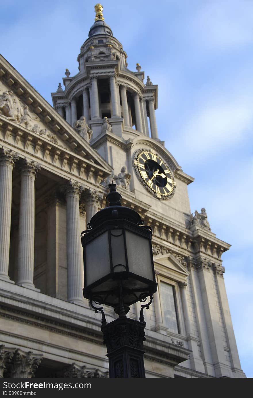 St. Paul's Cathedral Clock Tower glistens in the sunlight with a streetl lamp standing in front. St. Paul's Cathedral Clock Tower glistens in the sunlight with a streetl lamp standing in front