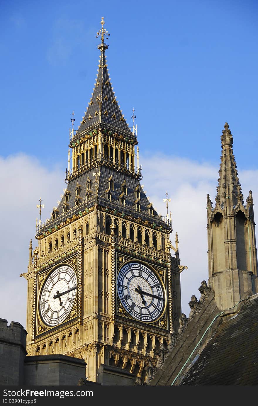 Big Ben tower peaks over the ornate rooftop of a nearby building in London England. Big Ben tower peaks over the ornate rooftop of a nearby building in London England.