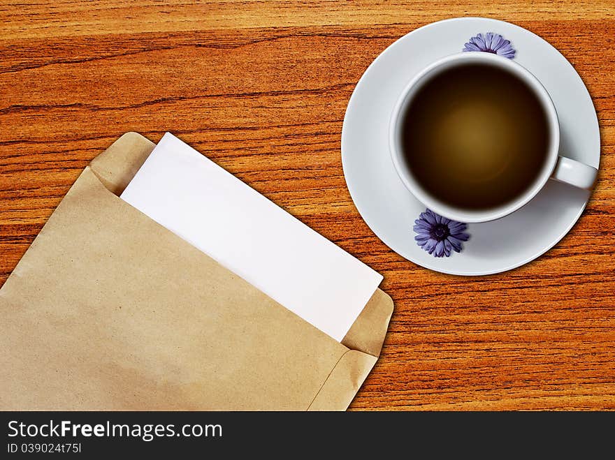 White cup of coffee and brown envelope document on wood table background