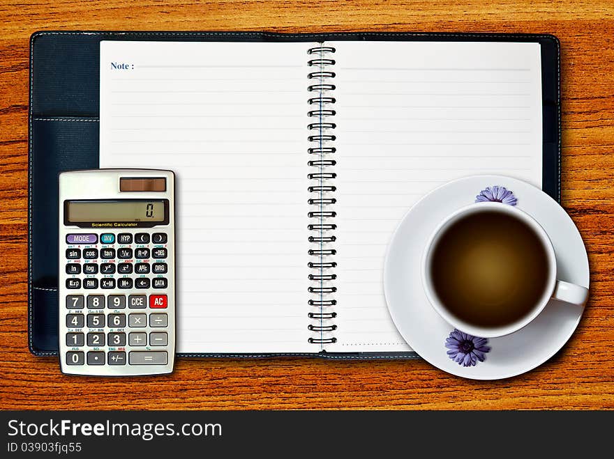 White cup of coffee and calculator on blank page notebook on wood table background