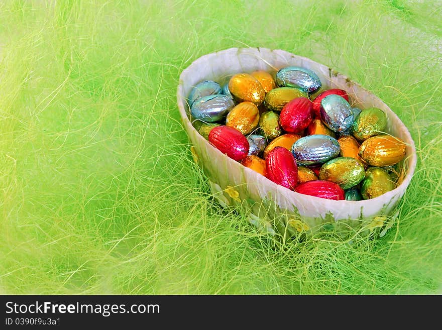 Chocolate eggs in the bowl on the imitation of hay