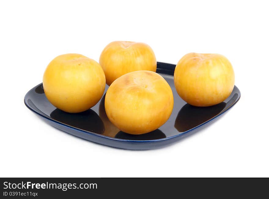 Yellow plums on a dark blue plate, isolated on a white background