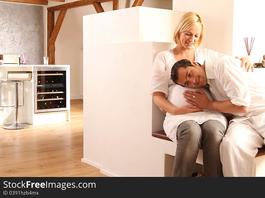 Young and happy pregnant couple sitting together at home