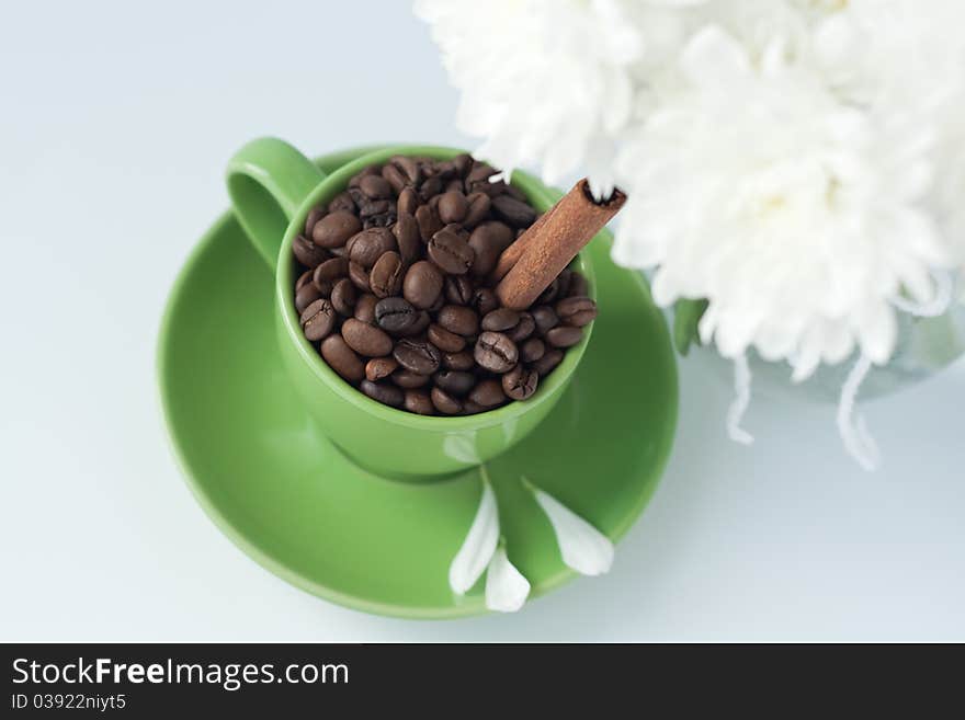 Coffee beans in a green cup on a white background