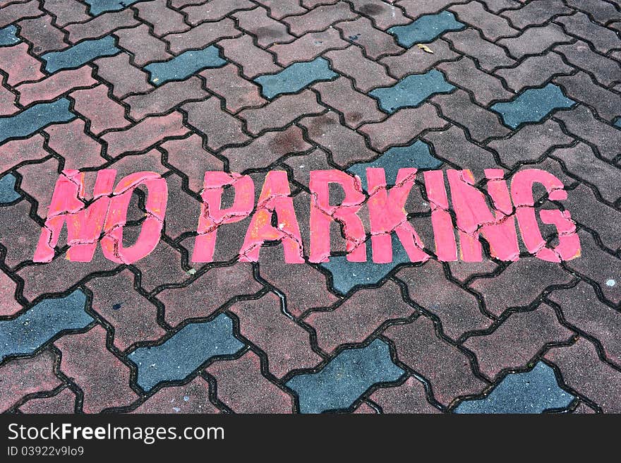 A Red Color No Parking Sign Painted On Road Tiles