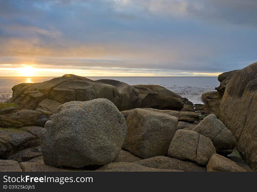 Sun setting over the ocean, with rock formations in the foreground. Sun setting over the ocean, with rock formations in the foreground